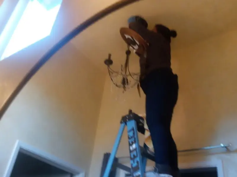 Electrician installing a chandelier in a Homestead residence